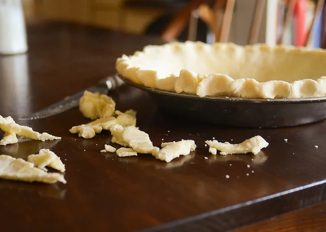 Overhead shot of a whole pumpkin pie in a pie dish, with a golden brown crust and smooth filling, ready to be served.