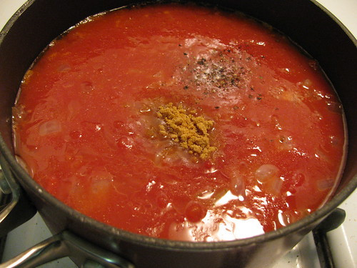 Adding canned tomatoes, tomato juice, and seasonings to the sautéed onions for Pioneer Woman Tomato Soup