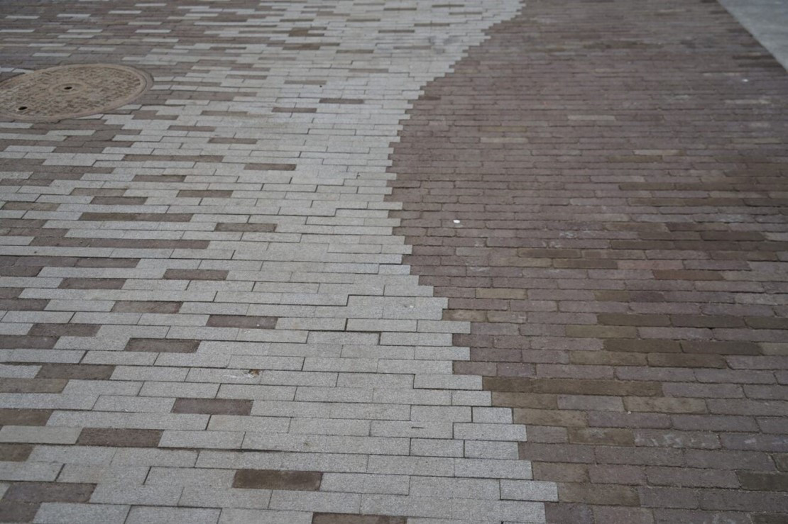 Close-up image showing two-toned pavers following the original shoreline in Pioneer Square South alleys, highlighting historical preservation.