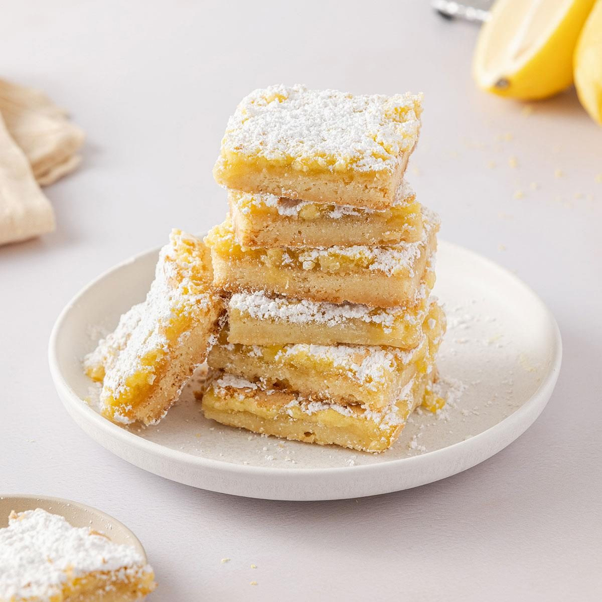 Lemon Bars, showing bright yellow lemon bars dusted with powdered sugar, arranged on a plate.