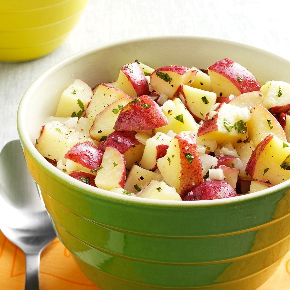 Lemony Potato Salad, potato salad with lemon vinaigrette, showing potatoes and herbs in a bowl.