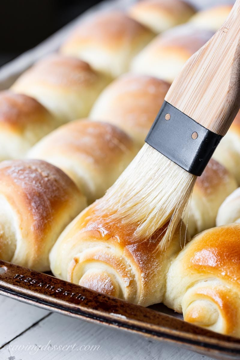 A pan of Lion House swirled rolls being brushed with melted butter