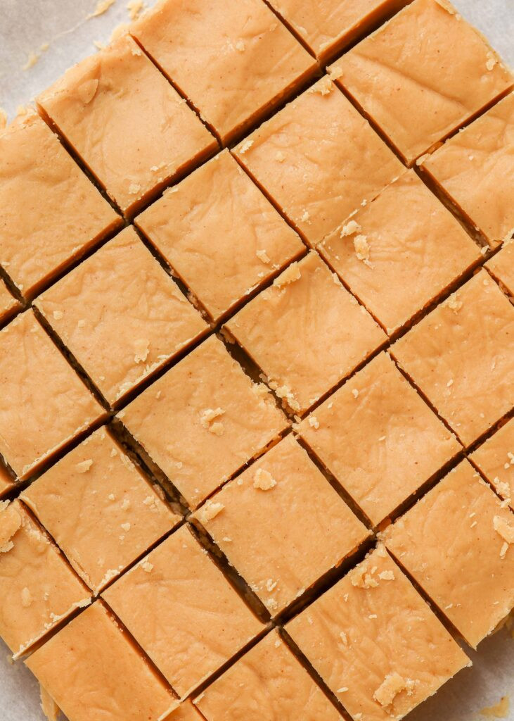 Squares of peanut butter fudge arranged on a wooden cutting board, ready to be served and enjoyed.