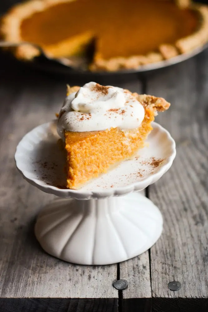 Close-up of a slice of pumpkin pie with a fork, showcasing the smooth texture and rich color.