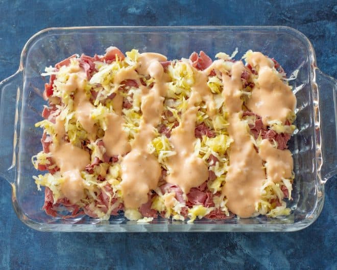 Thousand Island dressing being drizzled, an essential component of a Reuben Casserole inspired by Pioneer Woman