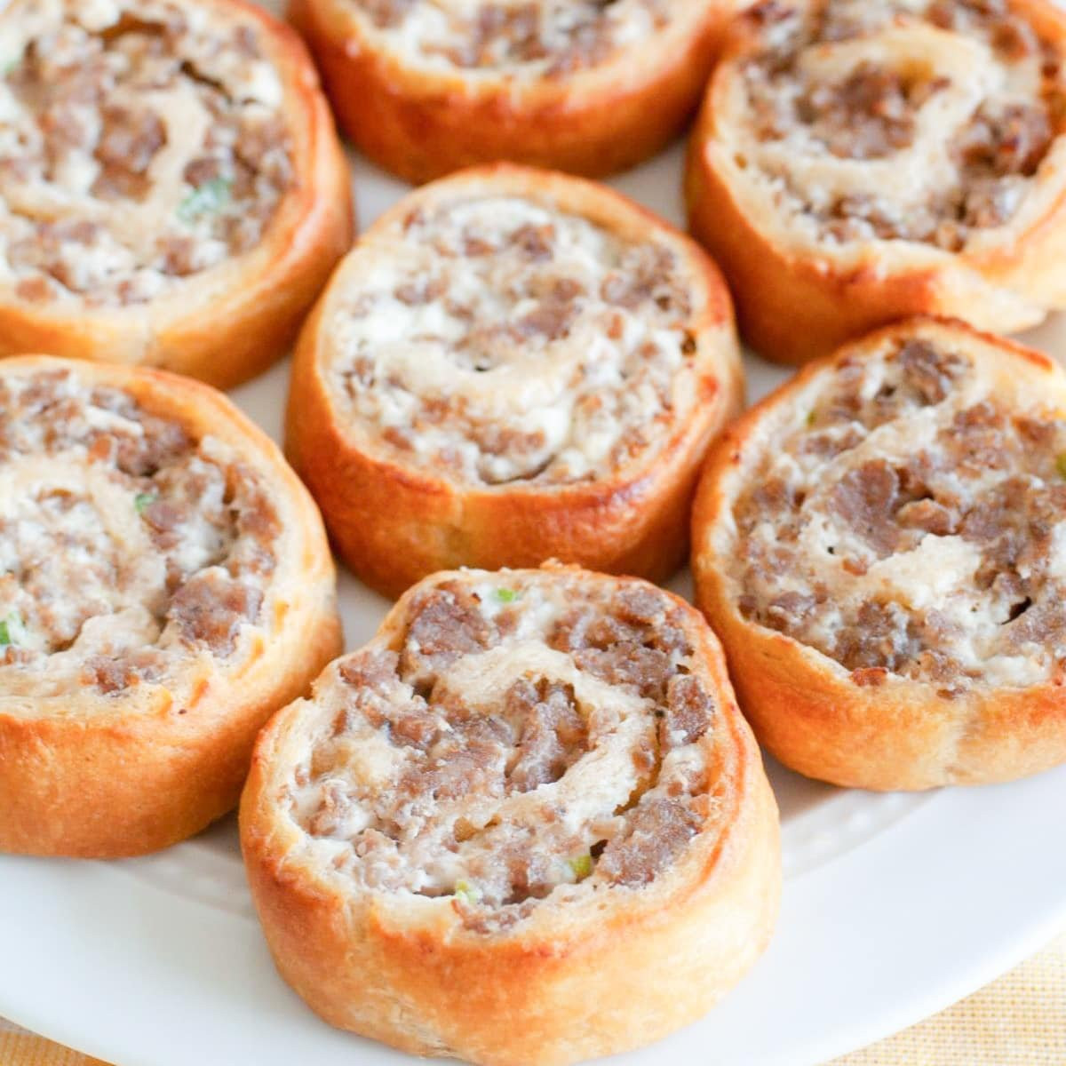 Sausage pinwheel appetizers on a white plate, ready to serve.