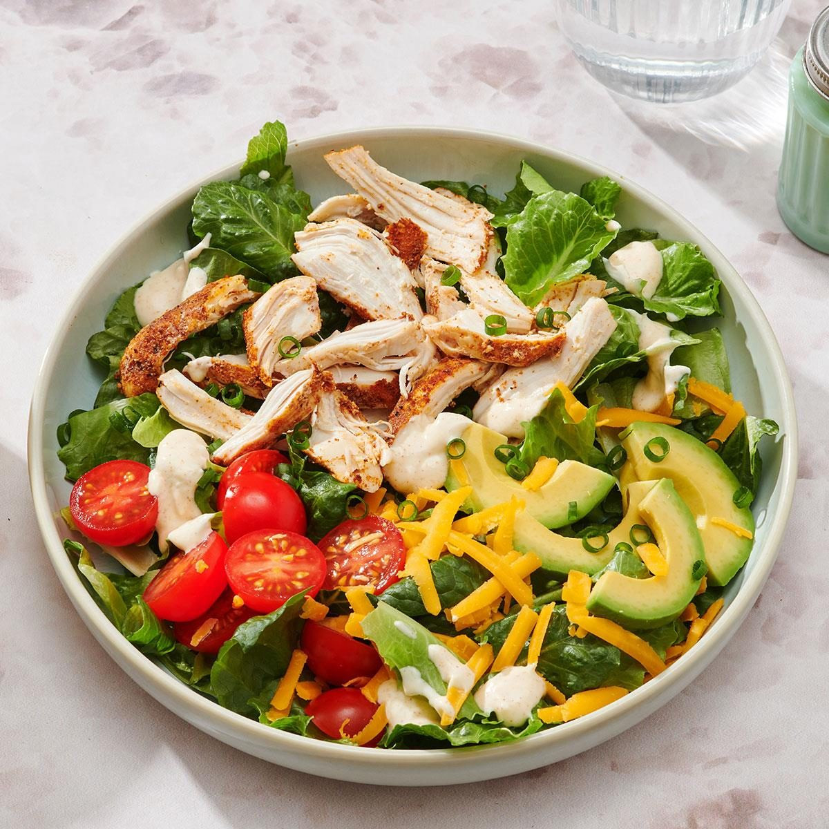 Chicken Taco Salad, a slow cooker chicken taco salad with toppings like lettuce, tomatoes, and cheese in a bowl.