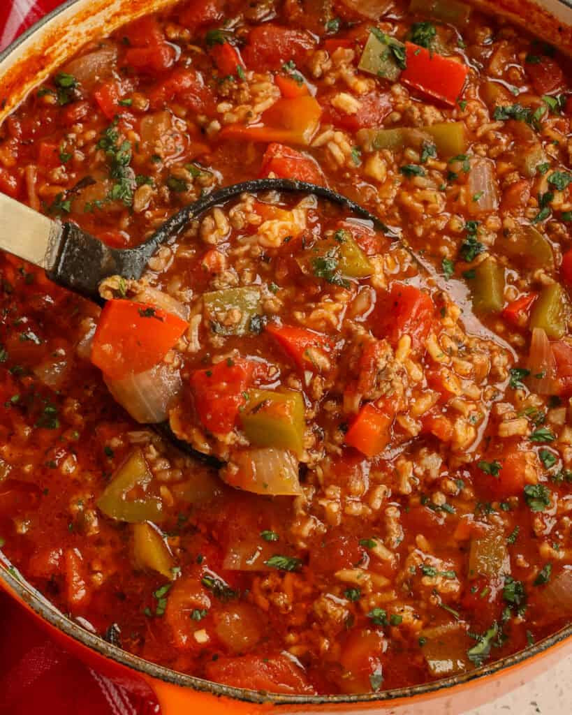 A Dutch oven and a ladle full of stuffed pepper soup. 