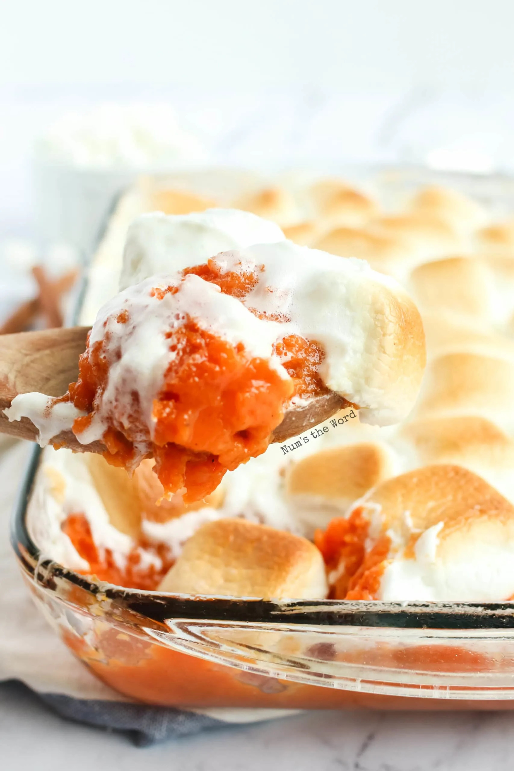 Scooping a serving of Pioneer Woman Sweet Potato Casserole with toasted marshmallows from baking dish