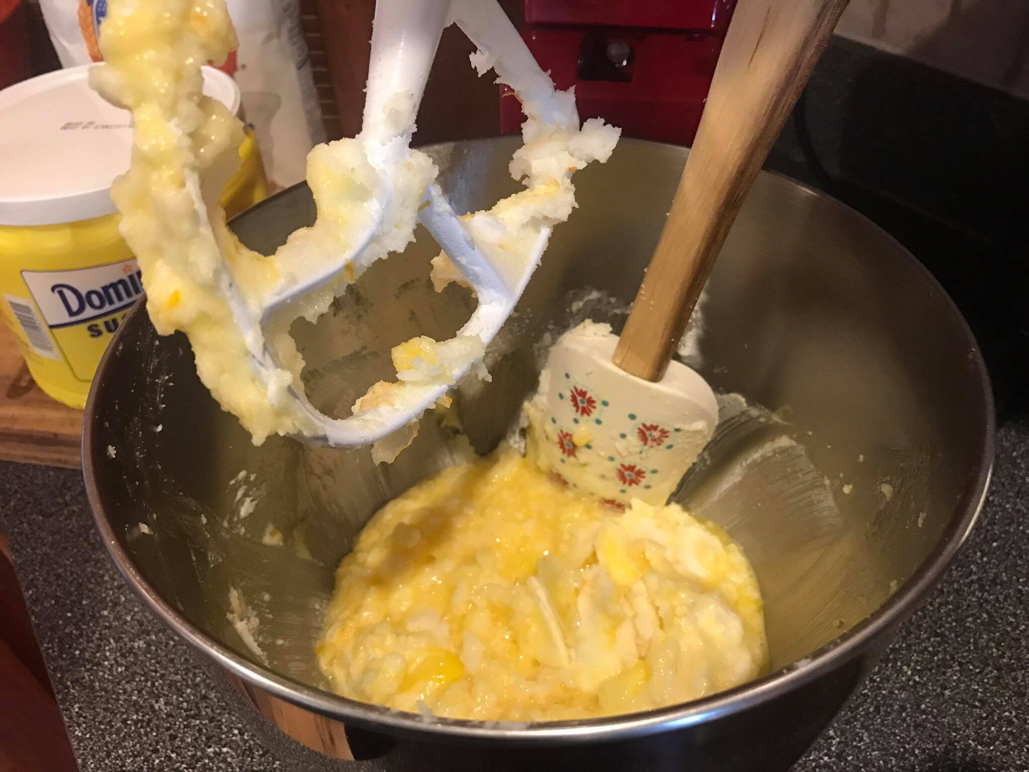 Scraping down the sides of the mixing bowl during sugar cookie dough preparation