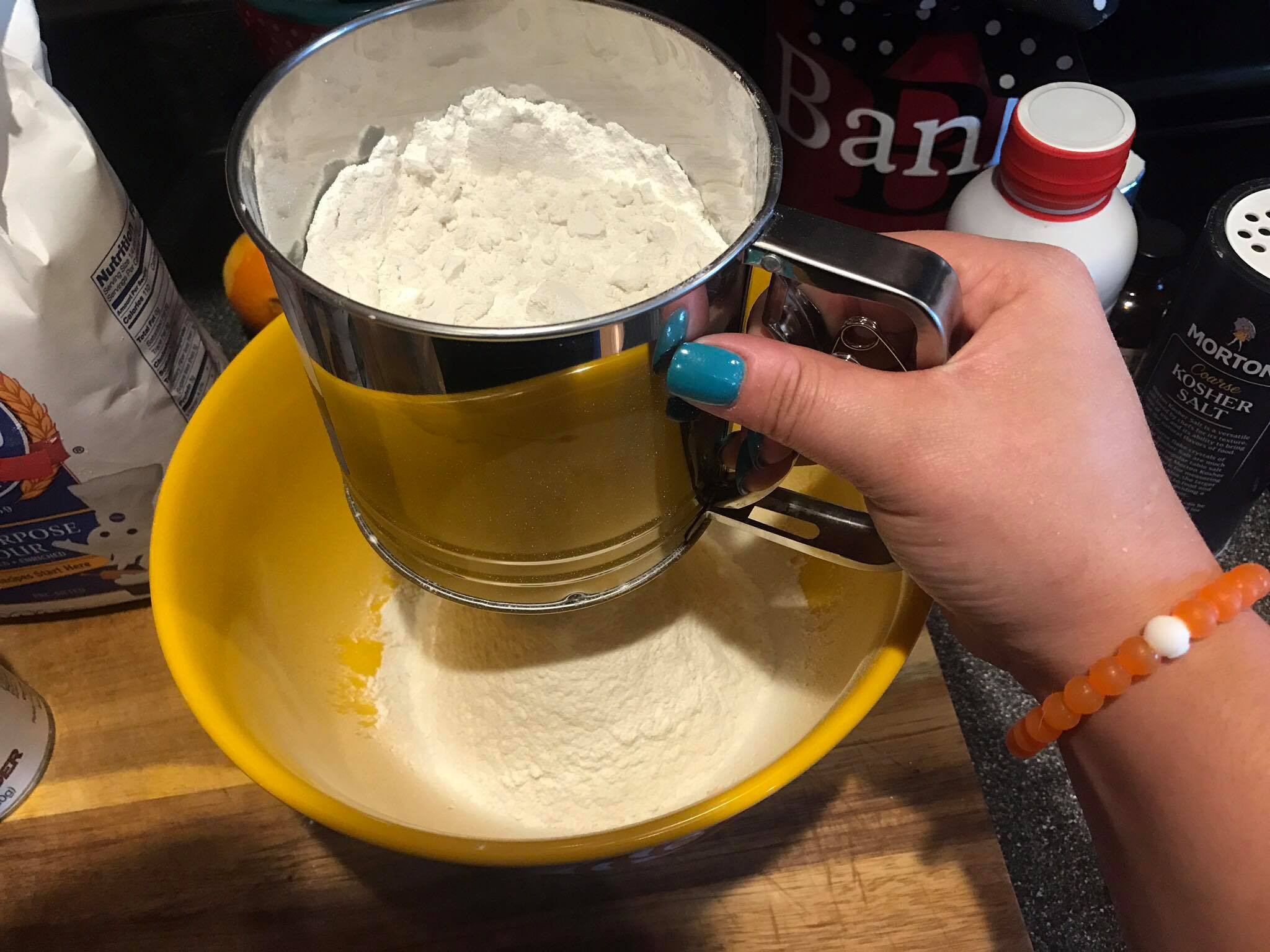 Adding sifted dry ingredients to the wet ingredients in a mixing bowl