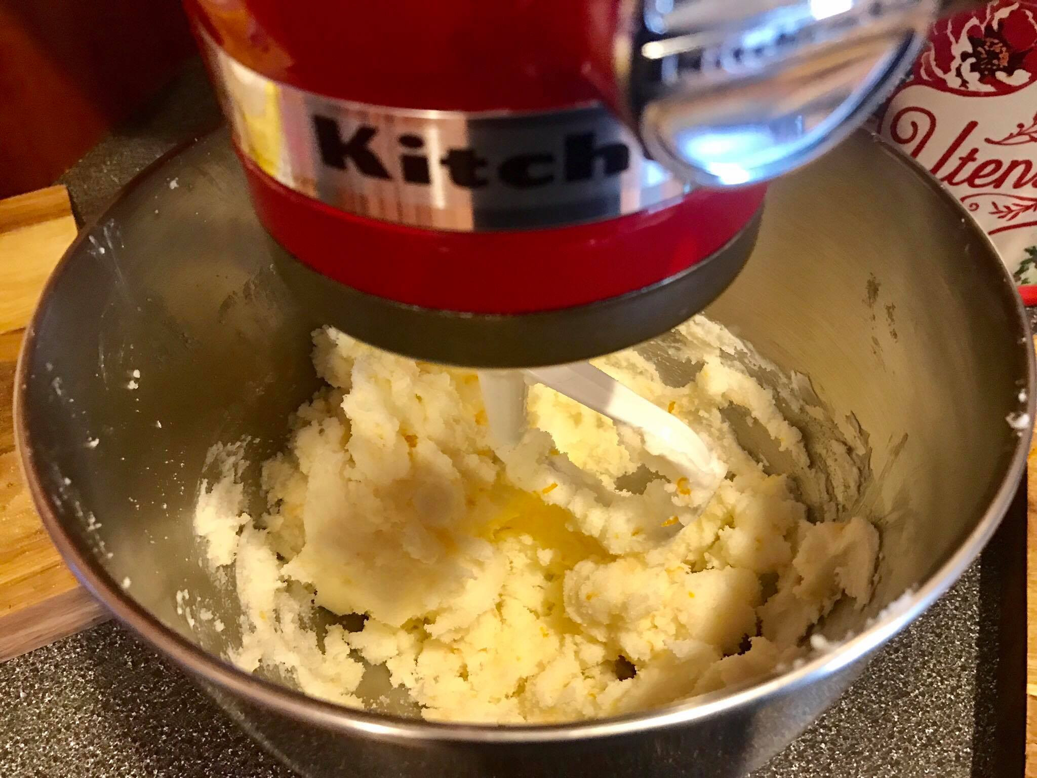 Smooth and creamy mixture of sugar, shortening, and orange zest in a mixing bowl