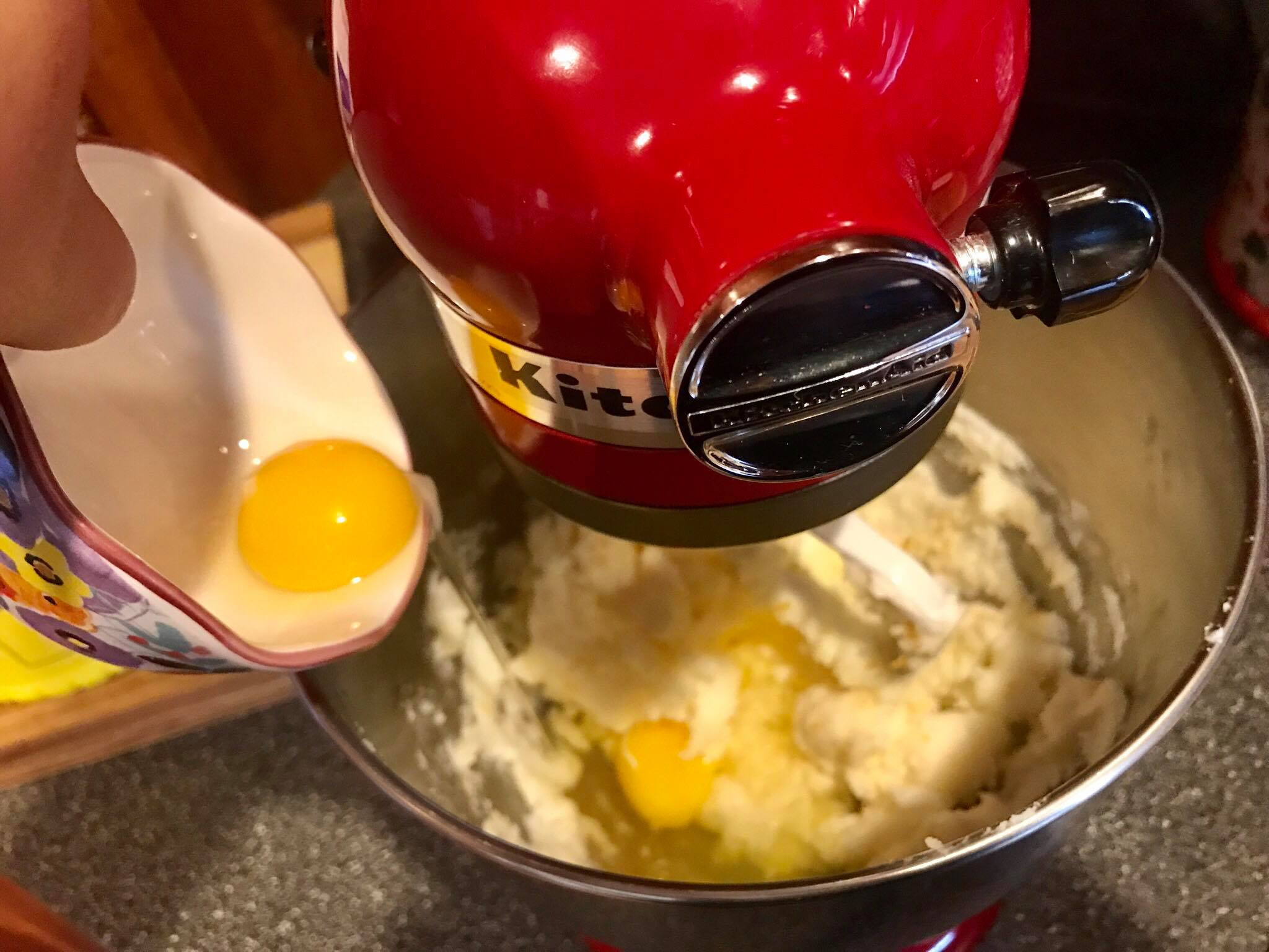 Cracking eggs into the mixing bowl for sugar cookie dough