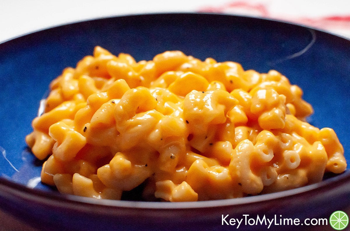 A side shot of gooey mac and cheese on a blue plate.