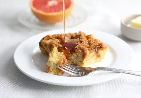 Overnight french toast casserole with syrup being drizzled, showcasing its golden-brown crust and soft interior