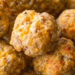 A pile of Bisquick sausage cheese balls on a plate with dipping sauces on the side