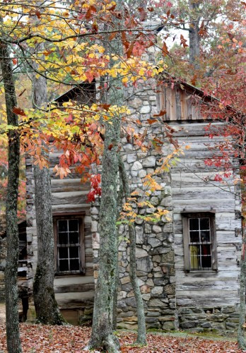 A log cabin in a fall setting at Hart Square, illustrating the village's picturesque and historical atmosphere