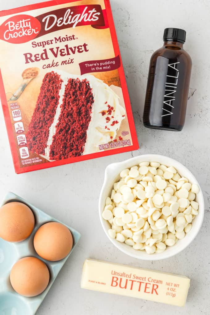 Simple ingredients for red velvet cake mix bars: cake mix, vanilla, white chocolate chips, eggs, and butter.
