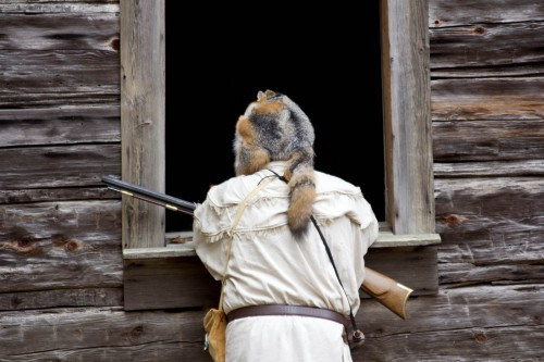 A figure dressed as Daniel Boone at Hart Square Pioneer Village, representing historical figures and frontier life