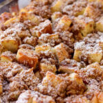 French toast casserole topped with powdered sugar, presented in a baking dish, showcasing its golden-brown crust and inviting texture.