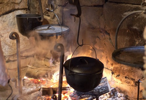 Hearth cooking demonstration, showcasing traditional cooking methods inside a pioneer cabin