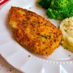 Crisp Parmesan Crusted Chicken on a dinner plate with mashed potatoes and broccoli.